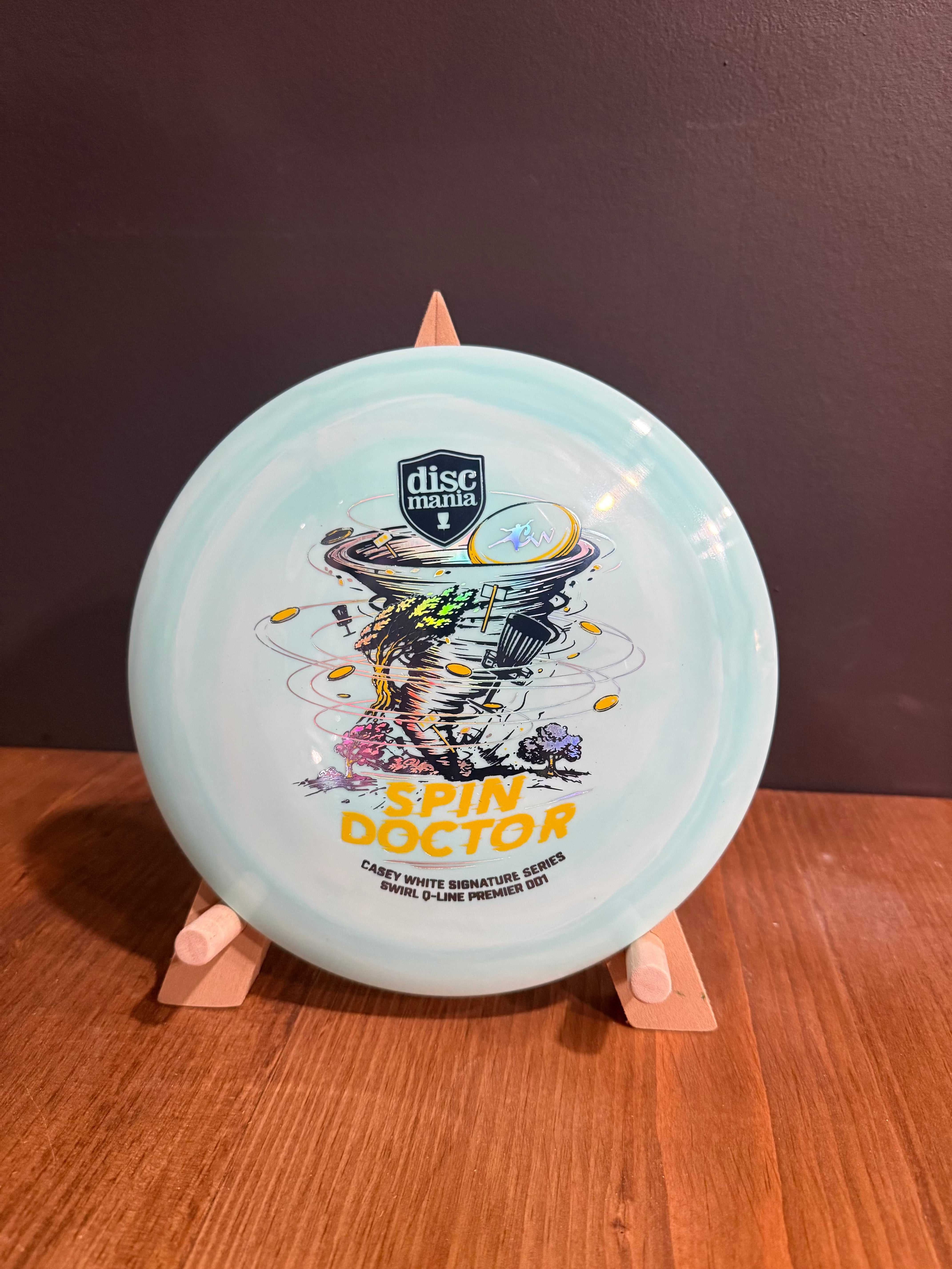 Spin Doctor distance driver disc in pale blue swirled plastic with colourful triple-foil signature artwork and stamp