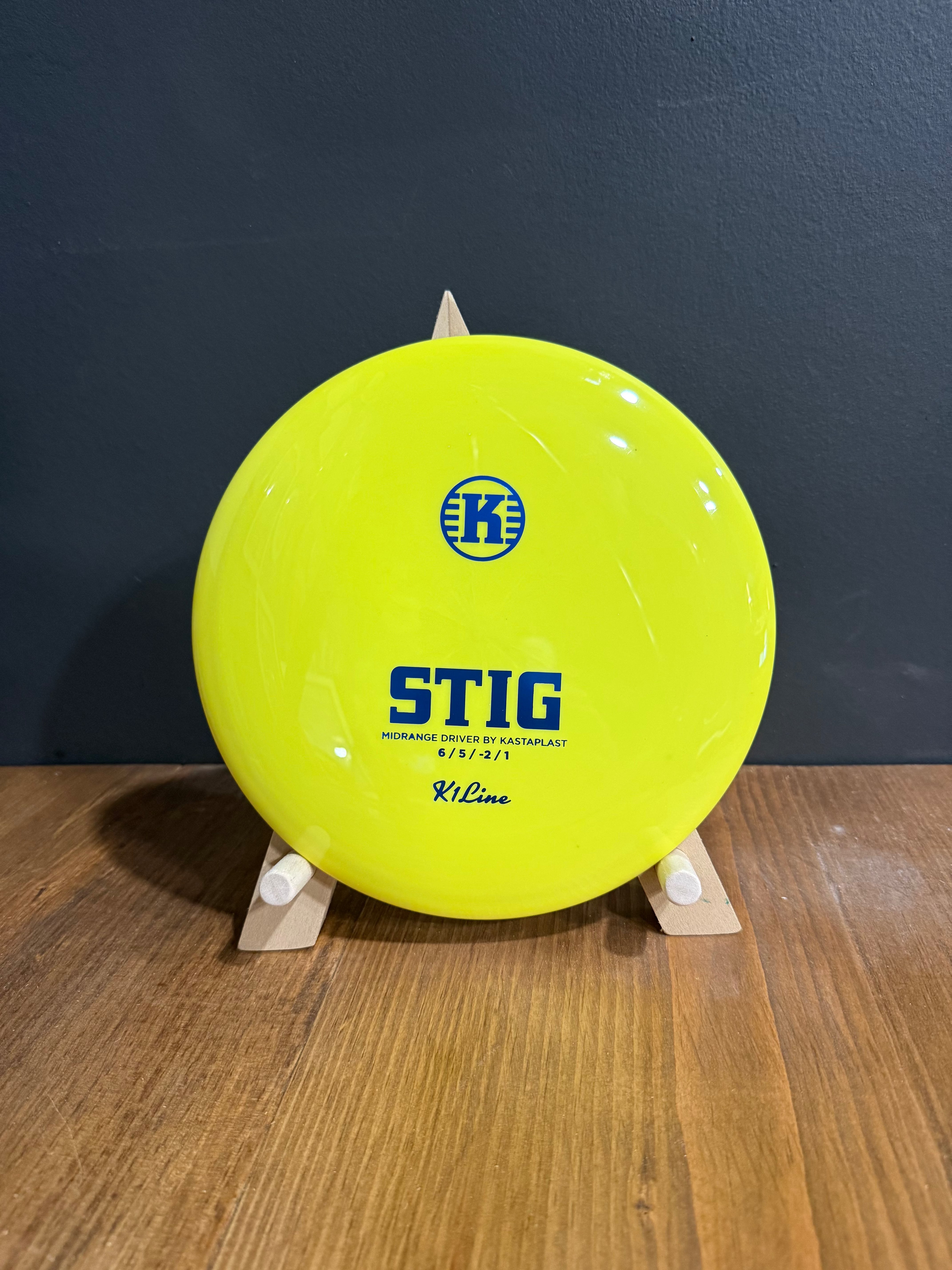 K1 Stig yellow disc golf driver with glossy plastic, blue logo and bold blue STIG lettering over stamped flight details